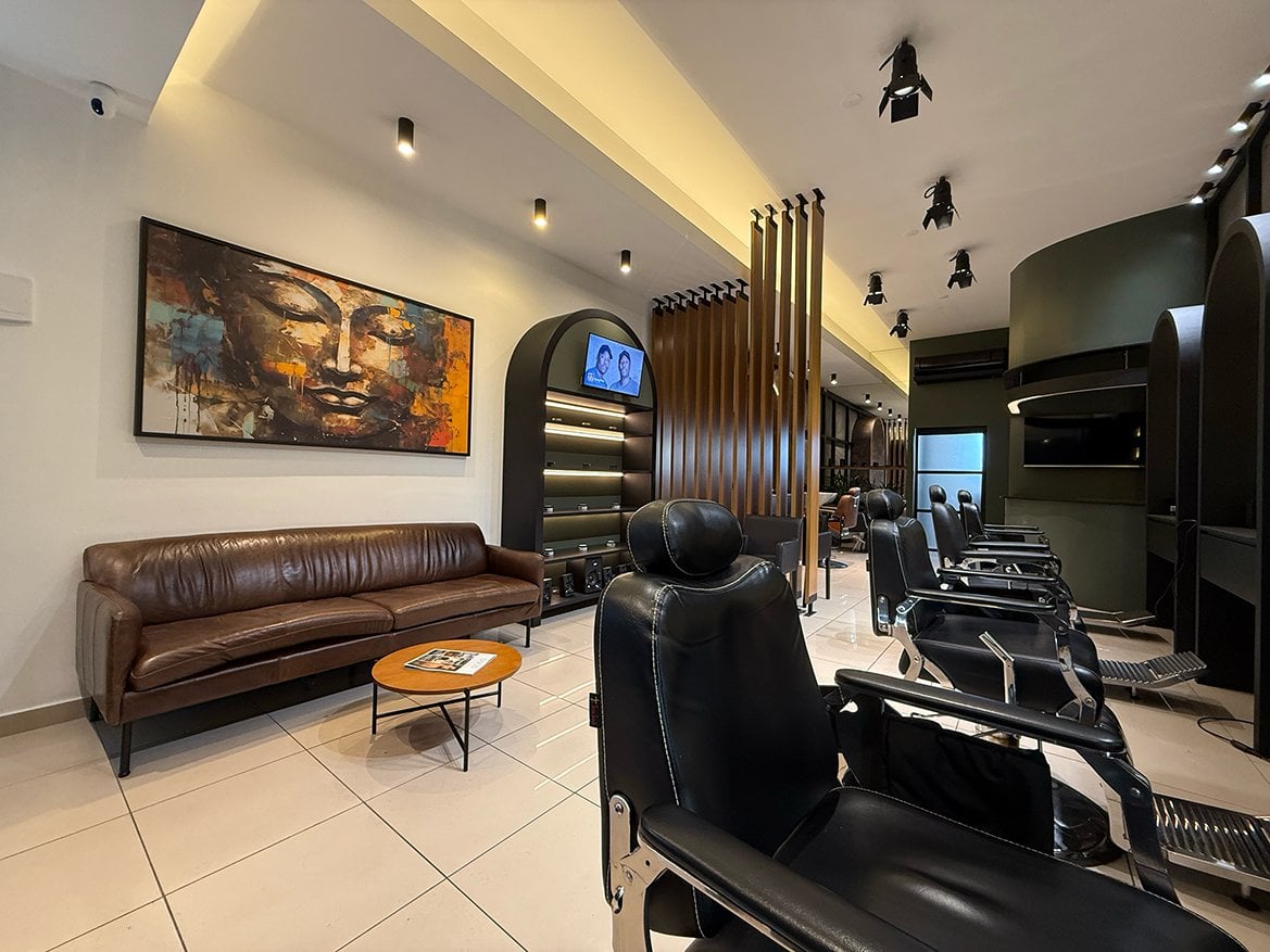 Interior da Kóden Barbearia, sofá de couro, cadeiras e estações de corte